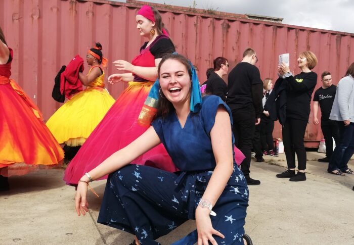 An image of Sally, a dance artist, crouching and smiling