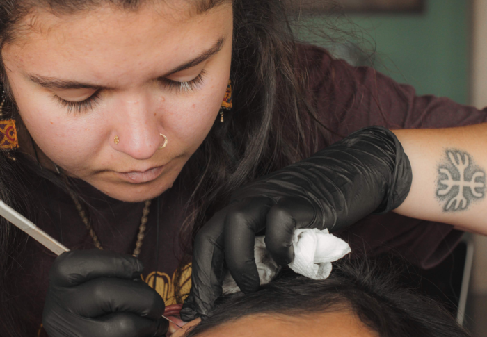 Andrianna, one of our Future Leader participants, tattooing someone's ear