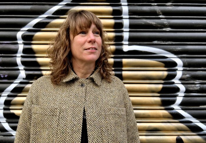 Sarah stood in front of a piece of gold street art, looking up to the right