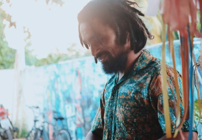 Brazilian artist Guga Santos smiling wearing a fabric painted shirt he has made