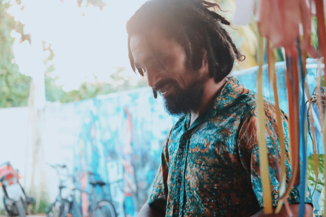 Brazilian artist Guga Santos smiling wearing a fabric painted shirt he has made