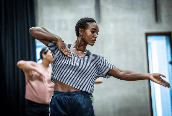 Contemporary dancer, Ruth Asidi, dancing with one arm outstretched and the other elbow high retracted