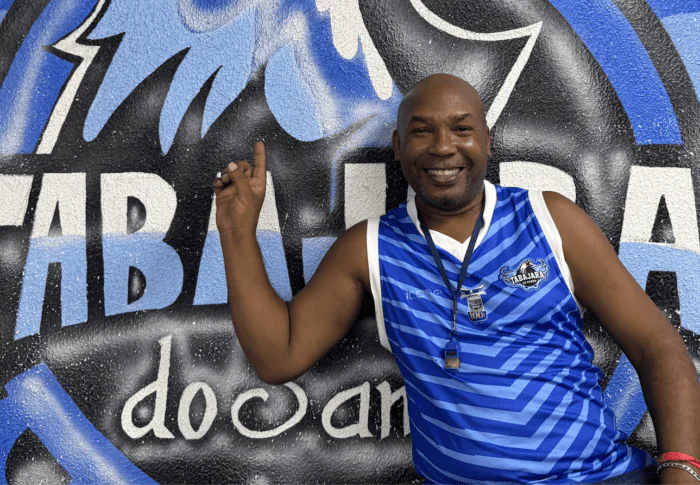 Mestre Nilo from Portela samba school pointing to a giant eagle mural